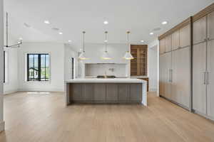Kitchen with light wood-type flooring, light countertops, recessed lighting, baseboards, and a sink