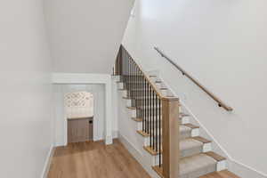 Staircase with a high ceiling, wood finished floors, and baseboards