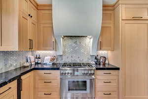 Kitchen with backsplash, high end stainless steel range oven, and light brown cabinetry