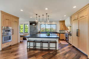 Kitchen featuring dark hardwood / wood-style flooring, sink, a breakfast bar area, a kitchen island, and high quality appliances