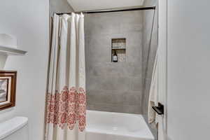 Bathroom featuring toilet and shower / bath combo with shower curtain