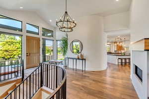 Interior space featuring plenty of natural light, high vaulted ceiling, light wood-type flooring, and a chandelier