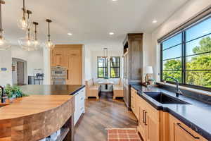 Kitchen with decorative light fixtures, wood-type flooring, sink, light brown cabinets, and double oven