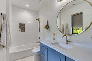 Full bathroom featuring tile patterned flooring, tiled shower / bath, toilet, and vanity. Attached to bedroom