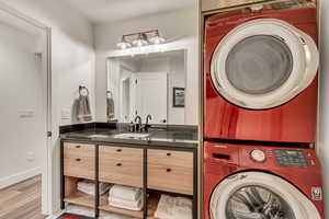 Laundry room with light hardwood / wood-style flooring, sink, and stacked washer / drying machine