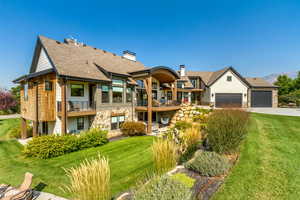 Rear view of property with a yard, a garage, and a balcony