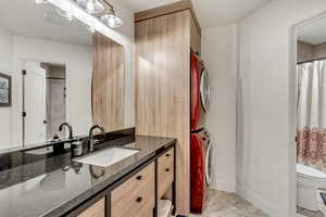 Hall Bathroom featuring toilet, tile patterned floors, vanity, stacked washer / drying machine, and a shower with curtain