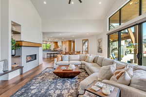 Living room with high vaulted ceiling, hardwood / wood-style flooring, and ceiling fan