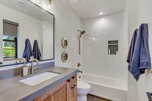 Full bathroom featuring tiled shower / bath, toilet, vanity, and tile patterned floors. Attached to bedroom.