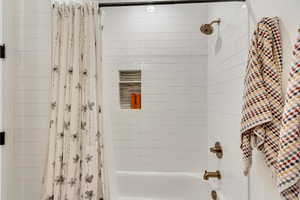 Bathroom with shower / tub combo with curtain. Attached to level 1 bedroom