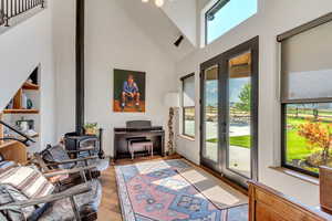 Living room with french doors, high vaulted ceiling, a wealth of natural light, and a wood stove