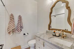 Bathroom with vanity, toilet, tile patterned floors, and a tile shower, attached to level 1 bedroom