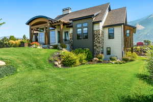 Rear view of house featuring a mountain view and a lawn