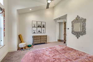 Carpeted bedroom featuring high vaulted ceiling and ceiling fan