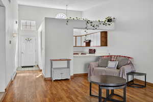 Sitting room featuring light wood-style floors, baseboard heating, and a high ceiling