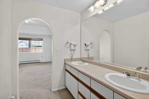 Bathroom with light carpet, double vanity, and a baseboard radiator