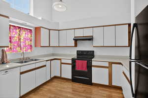 Dual tone kitchen featuring dual tone cabinetry, black appliances, light countertops, and light wood finished floors