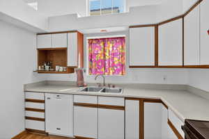 Kitchen featuring dual tone cabinetry, healthy amount of natural light, dishwasher, black range oven, and light countertops