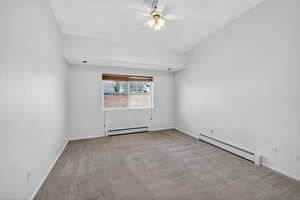 Empty room featuring a baseboard radiator, light colored carpet, and ceiling fan