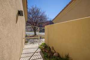 View of property exterior with stucco siding, a gate, and a balcony