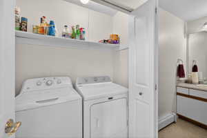 Laundry area with a baseboard heating unit and washer and dryer