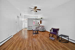 Living area with baseboard heating, light wood finished floors, and ceiling fan