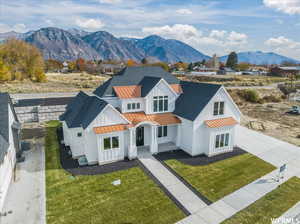 View of front of property featuring a mountain view, central air condition unit, and a front yard