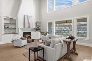 Living room with a fireplace, a healthy amount of sunlight, ceiling fan, and light hardwood / wood-style floors