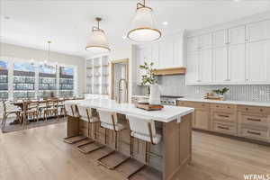 Kitchen featuring a kitchen island with sink, an inviting chandelier, hanging light fixtures, a breakfast bar area, and light hardwood / wood-style floors