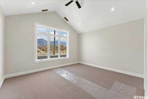 Empty room featuring a mountain view, vaulted ceiling, ceiling fan, and carpet flooring