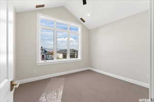 Empty room with carpet flooring and vaulted ceiling