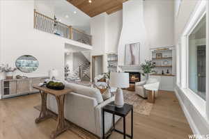 Living room featuring light hardwood / wood-style flooring, a fireplace, wooden ceiling, and a towering ceiling