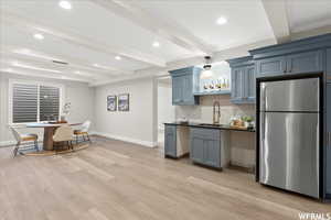 Kitchen with stainless steel fridge, beamed ceiling, light hardwood / wood-style flooring, and sink