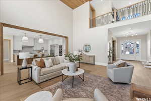 Living room with a towering ceiling, light wood-type flooring, a chandelier, and sink