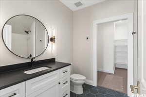 Bathroom featuring vanity, toilet, tile patterned floors, and walk in shower