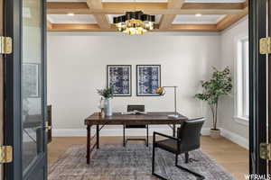 Office space featuring coffered ceiling, beamed ceiling, hardwood / wood-style floors, ornamental molding, and a chandelier