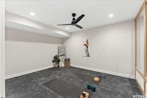 Workout room with ceiling fan and dark colored carpet