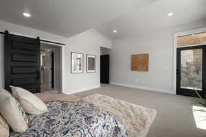 Bedroom featuring a barn door, lofted ceiling, and carpet