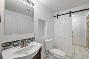 Bathroom featuring toilet, decorative backsplash, a textured ceiling, and vanity