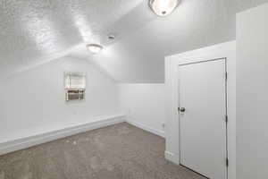 Additional living space with carpet, a textured ceiling, cooling unit, and lofted ceiling