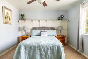 Bedroom featuring multiple windows, ceiling fan, and light carpet