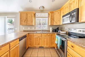 Kitchen with plenty of natural light, sink, light tile patterned floors, and appliances with stainless steel finishes