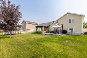 Rear view of property with a trampoline, central AC unit, a lawn, and a patio area