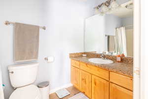 Bathroom featuring tile patterned flooring, vanity, toilet, and a shower with curtain