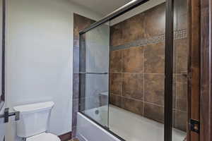 Bathroom featuring enclosed tub / shower combo and toilet