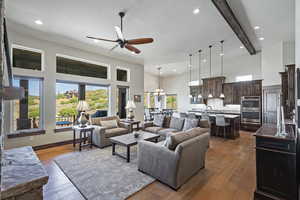 Living room with beamed ceiling, hardwood / wood-style floors, ceiling fan with notable chandelier, a textured ceiling, and sink