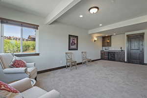 Living room featuring bar area, carpet flooring, and beam ceiling