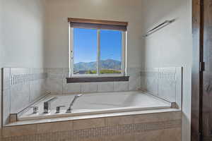 Bathroom with tiled tub and a mountain view