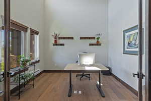 Office area featuring a wealth of natural light, a towering ceiling, and hardwood / wood-style floors