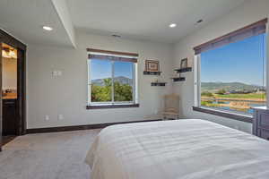 Carpeted bedroom featuring a textured ceiling, a mountain view, and ensuite bathroom